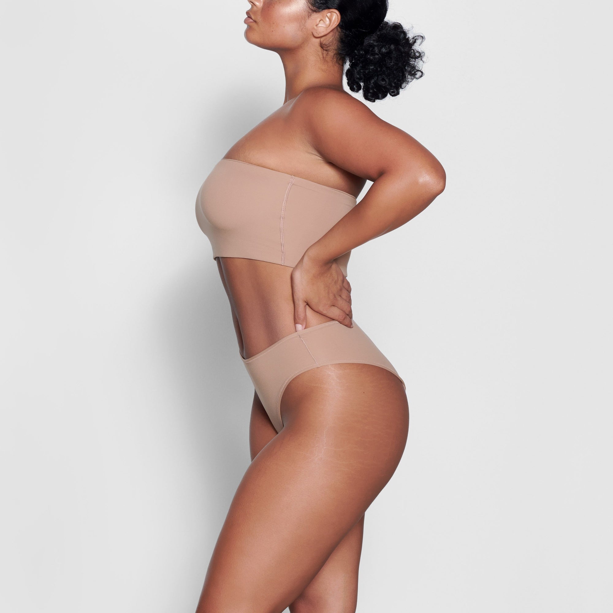 A MODEL STANDS SIDEWAYS SHOWING THE PROFILE OF THE FITS EVERYBODY BANDEAU BRA | SIENNA