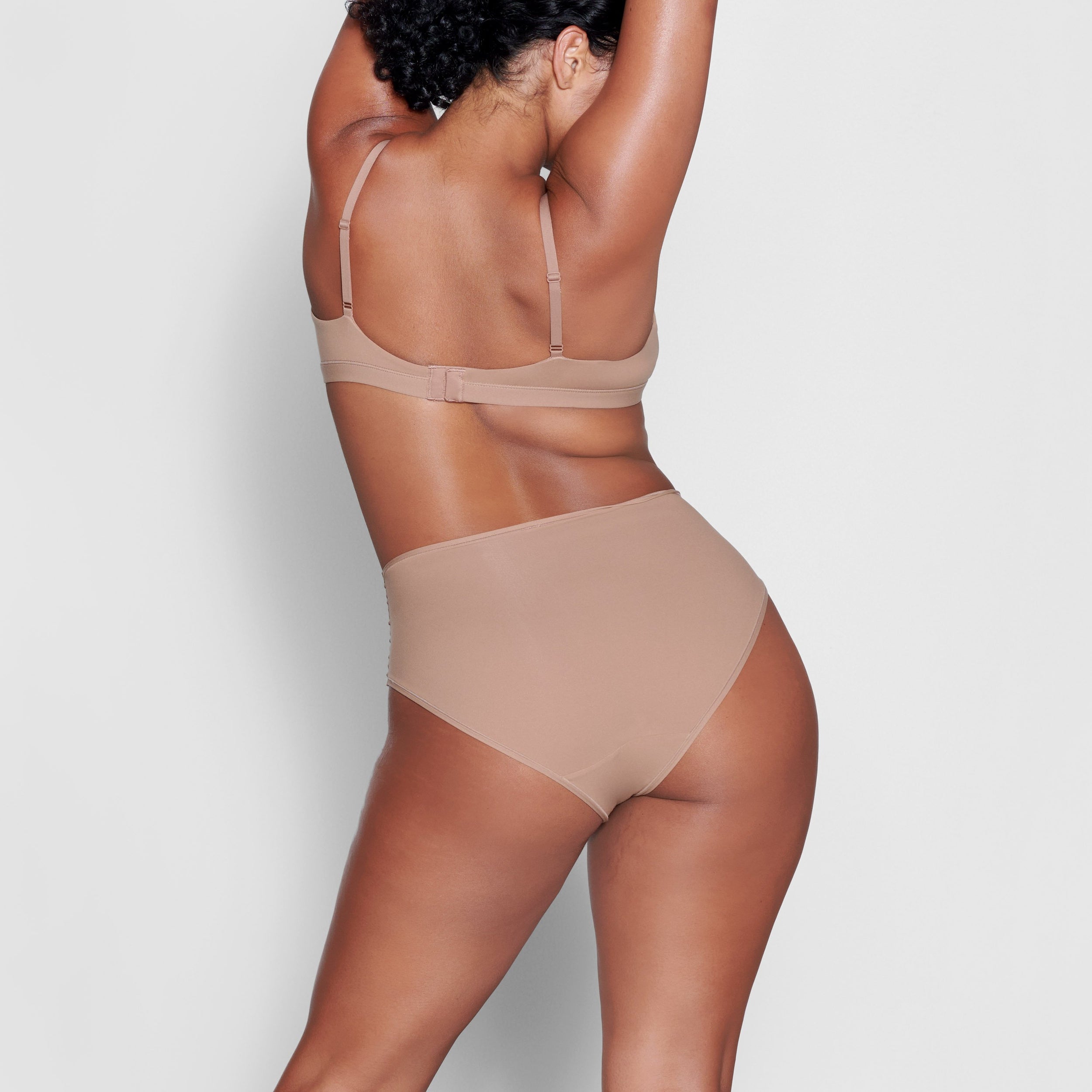 A MODEL STANDS WITH HER BACK TO THE CAMERA SHOWING THE FITS EVERYBODY CROSSOVER BRALETTE | SIENNA