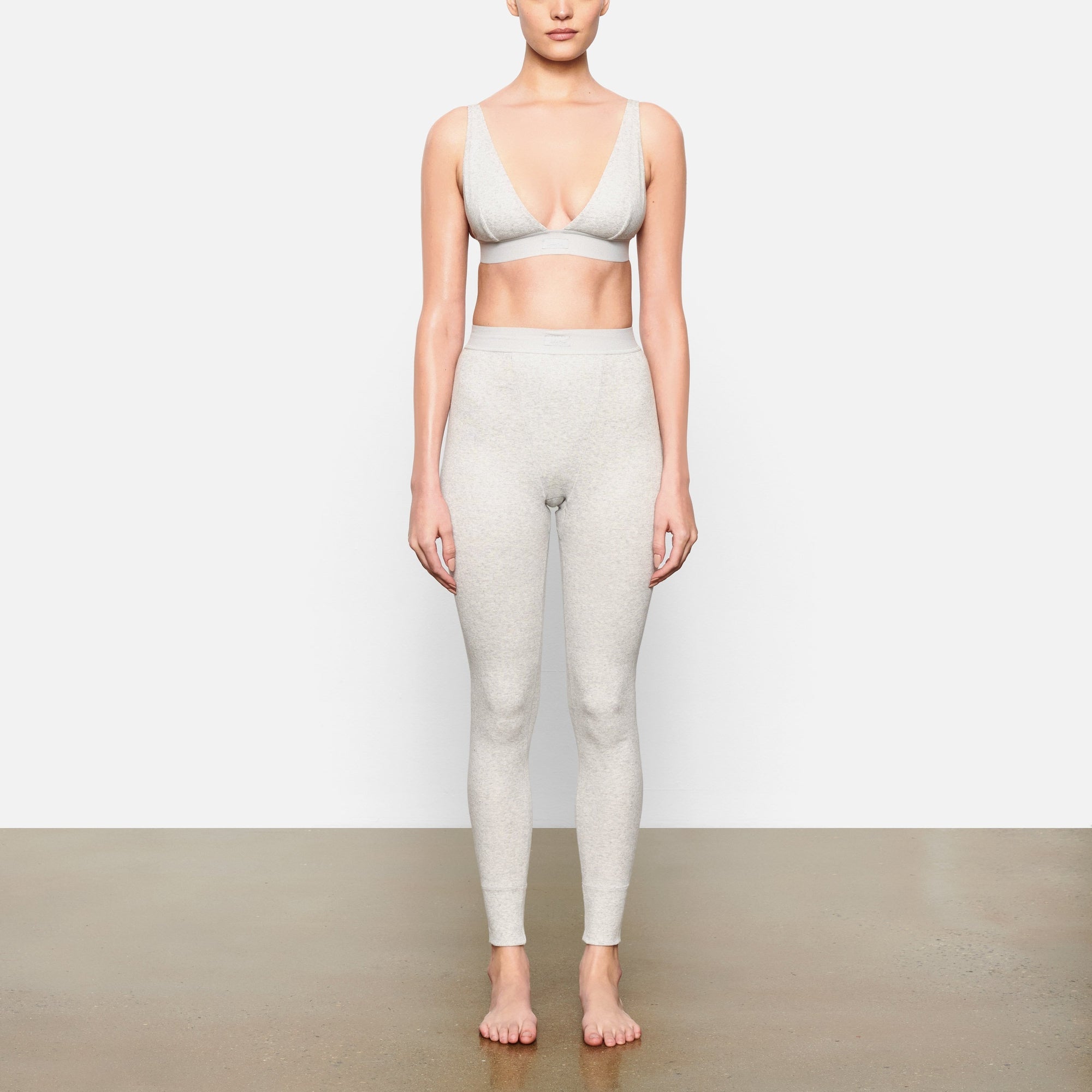 A MODEL STANDS FACING FORWARD WEARING THE COTTON RIB LEGGING | LIGHT HEATHER GREY