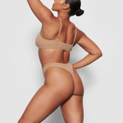 A MODEL STANDS SIDEWAYS SHOWING THE PROFILE OF THE FITS EVERYBODY THONG | SIENNA