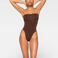 SEAMLESS SCULPT STRAPLESS THONG BODYSUIT WORN BY A MODEL IN FRONT VIEW 