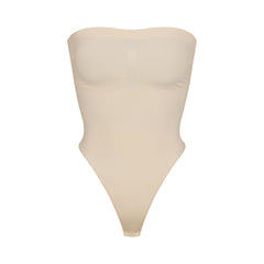 SEAMLESS SCULPT STRAPLESS THONG BODYSUIT | SAND (SHAPEWEAR BODYSUITS) LAYS FLAT ON A WHITE BACKGROUND | FLT