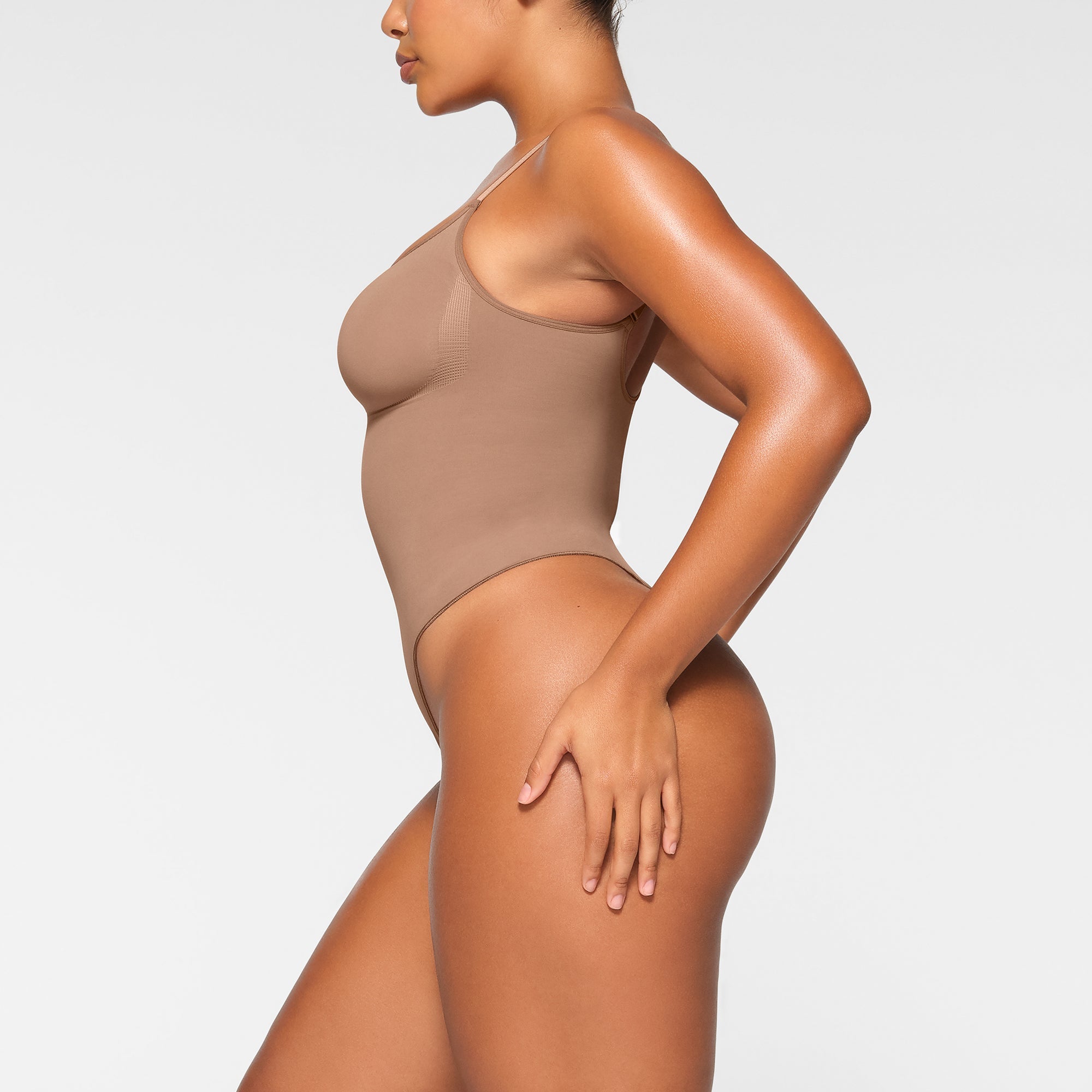 SEAMLESS SCULPT THONG BODYSUIT WORN BY A MODEL IN SIDE VIEW