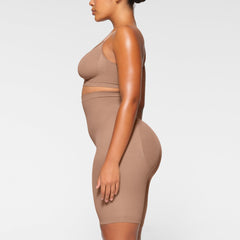 SEAMLESS SCULPT HIGH-WAISTED ABOVE THE KNEE SHORT WORN BY A MODEL IN SIDE VIEW
