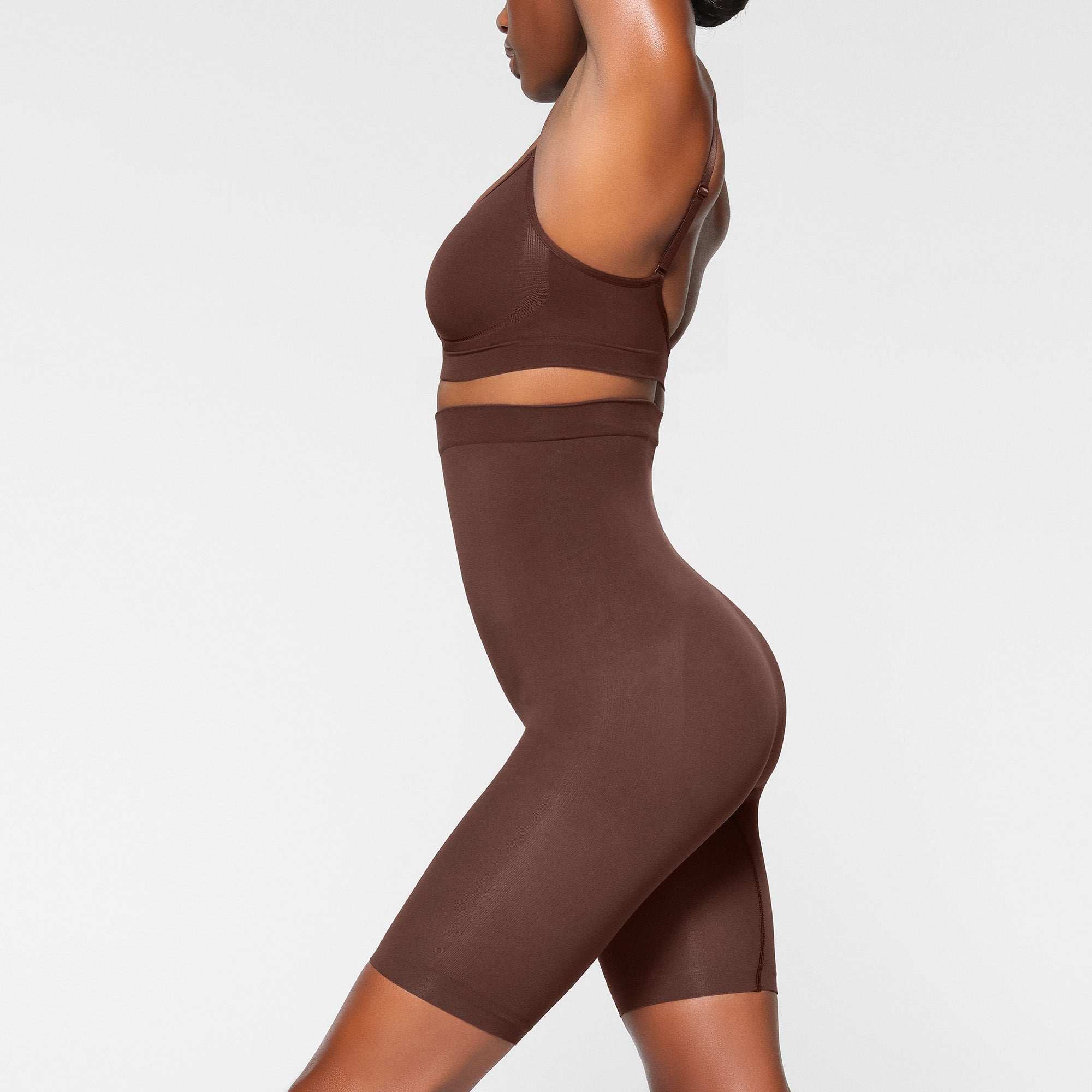 SEAMLESS SCULPT HIGH-WAISTED ABOVE THE KNEE SHORT WORN BY A MODEL IN SIDE VIEW