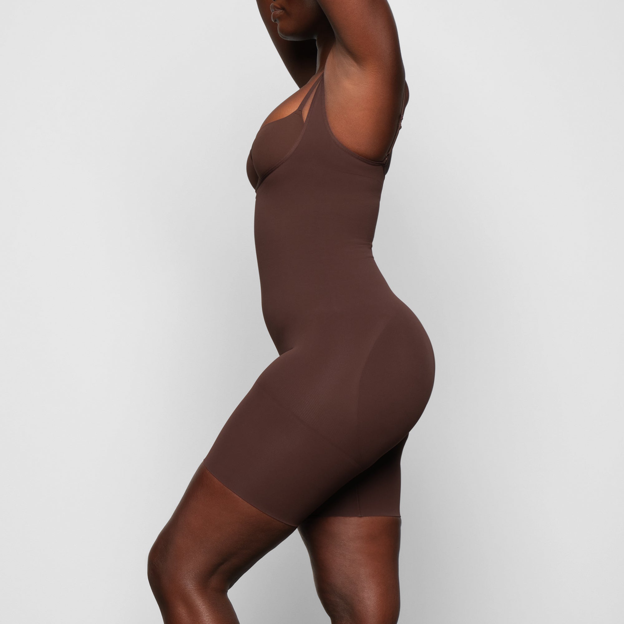 BUTT ENHANCING OPEN BUST BODYSUIT WORN BY A MODEL IN SIDE VIEW