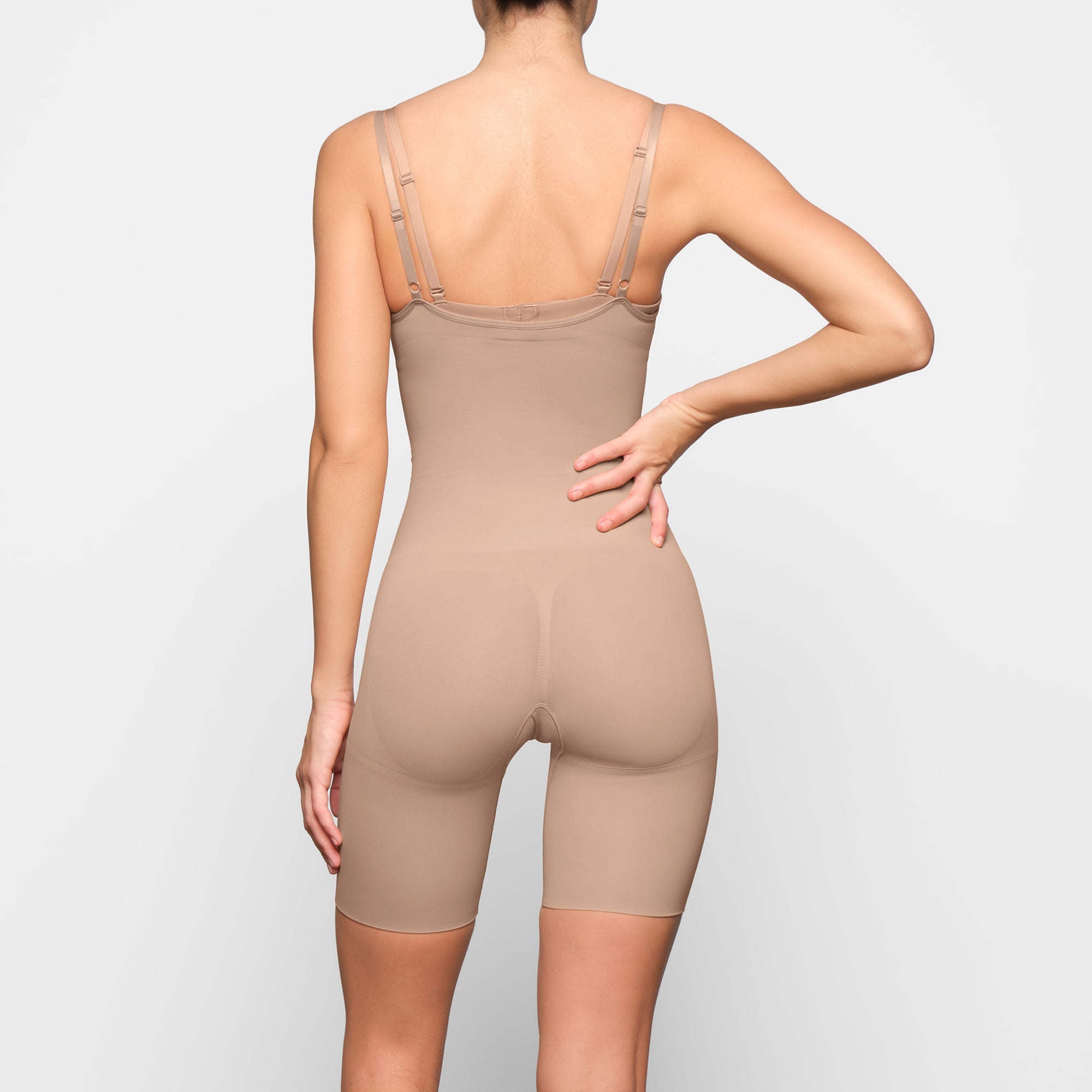 BUTT ENHANCING OPEN BUST BODYSUIT WORN BY A MODEL IN SIDE VIEW