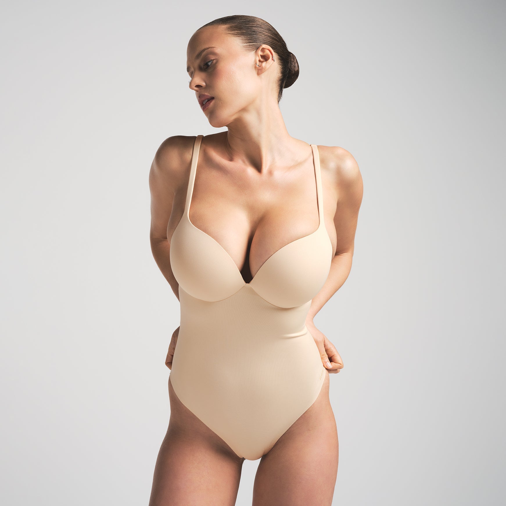 SKIMS ULTIMATE BODY PUSH-UP THONG BODYSUIT | SAND  ON A MODEL FRONT VIEW