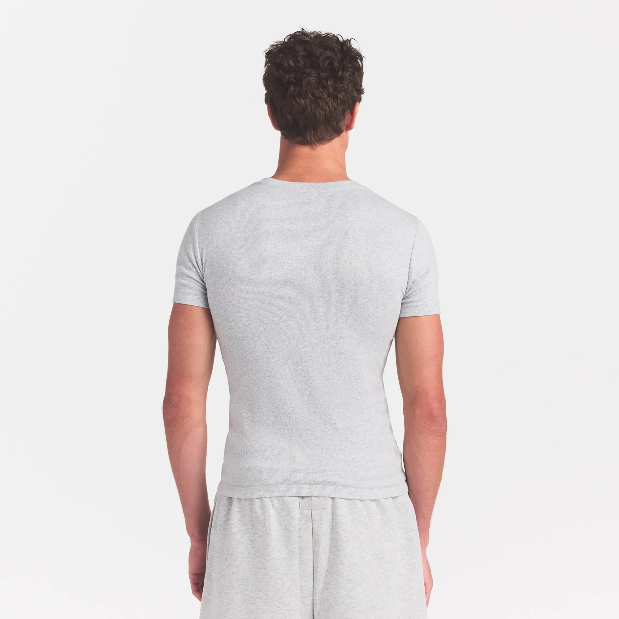 SKIMS COTTON RIB MENS T-SHIRT | LIGHT HEATHER GREY ON A MODEL SIDE VIEW @ | FOCUS: 0.0, 1.0, 0.9